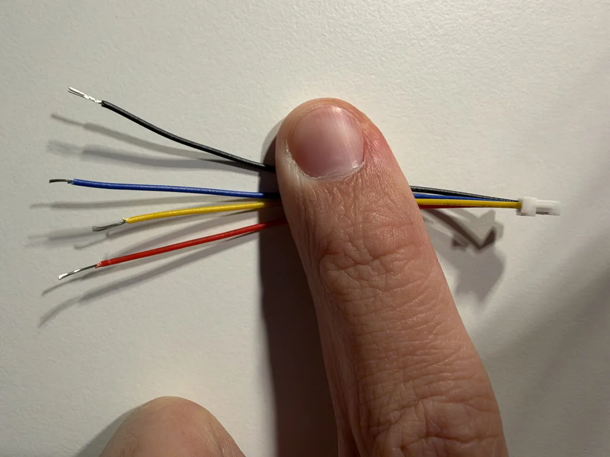 Four thin wires, black, blue, yellow and red, with 4 to 5 mm of bare copper at each end
